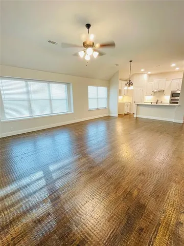 a view of empty room with wooden floor and fan