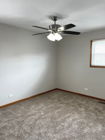 an empty room with a fan & a window