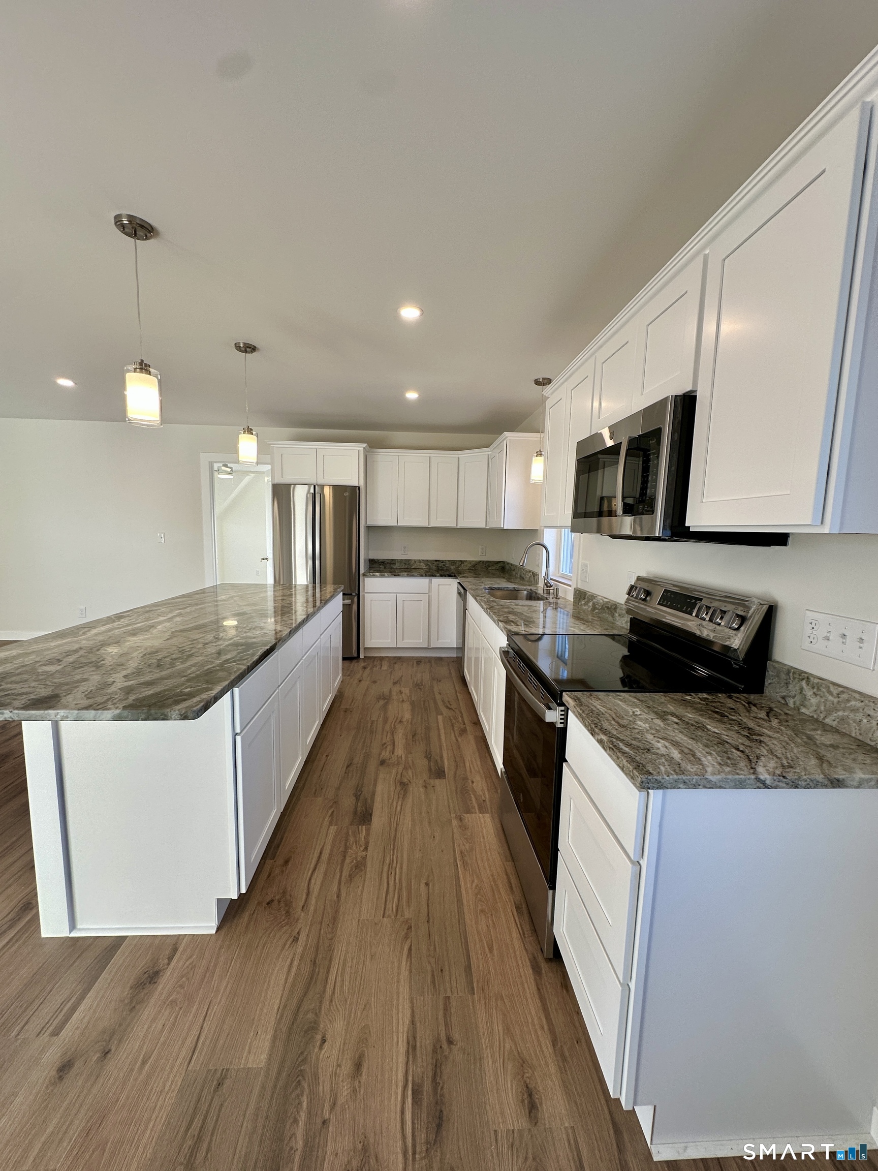 48 Cedar Street, Unit D Branford, CT 06405 - Photo 14 of 27 a large kitchen with stainless steel appliances granite countertop a stove a sink dishwasher and a microwave with wooden floor