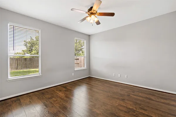 a view of an empty room with window and wooden floor