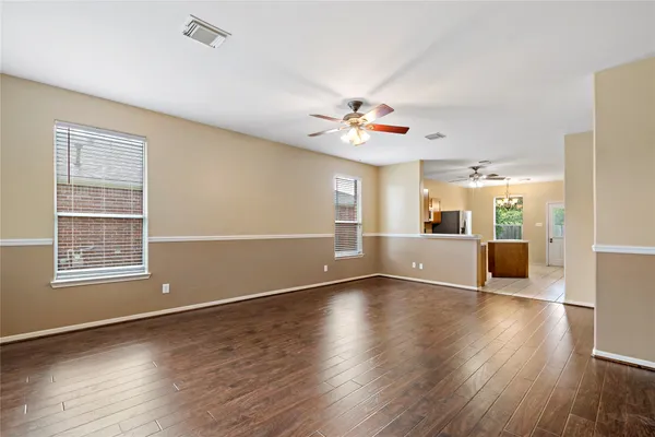 a view of an empty room with a window and wooden floor