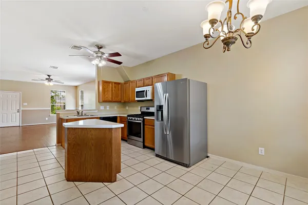 a kitchen with stainless steel appliances granite countertop a refrigerator a sink dishwasher a stove with a dining table and chairs