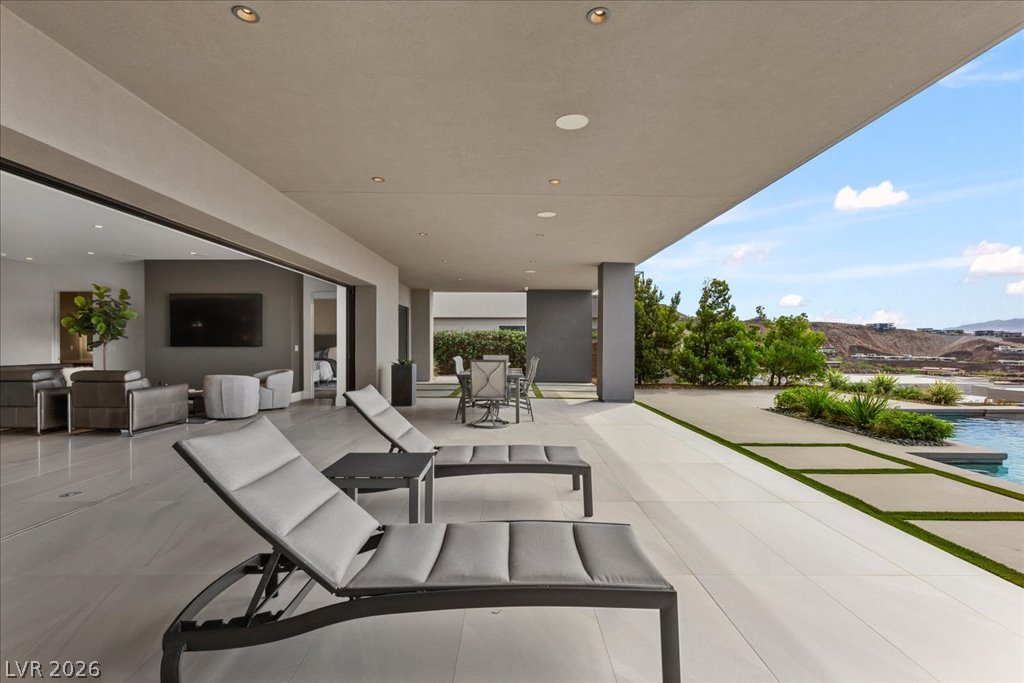 657 Ridgestone Rim Court Henderson, NV 89012 - Photo 82 of 97 Sliding doors connect the interior spaces seamlessly to a covered terrace and outdoor pool area.