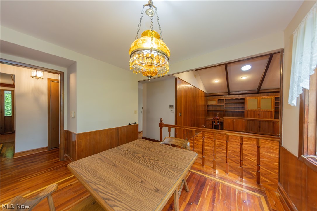 25001 Letchworth Road Beachwood, OH 44122 - Photo 13 of 50 Dining area featuring wood-finish flooring, half-wall wainscoting, and an ornate chandelier