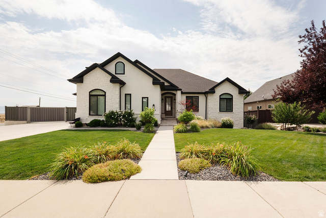 924 Country Lane Farmington, UT 84025 - Photo 2 of 91 Modern stucco exterior with black trim windows, a dark shingled roof, a concrete walkway, and a manicured lawn with varied landscaping