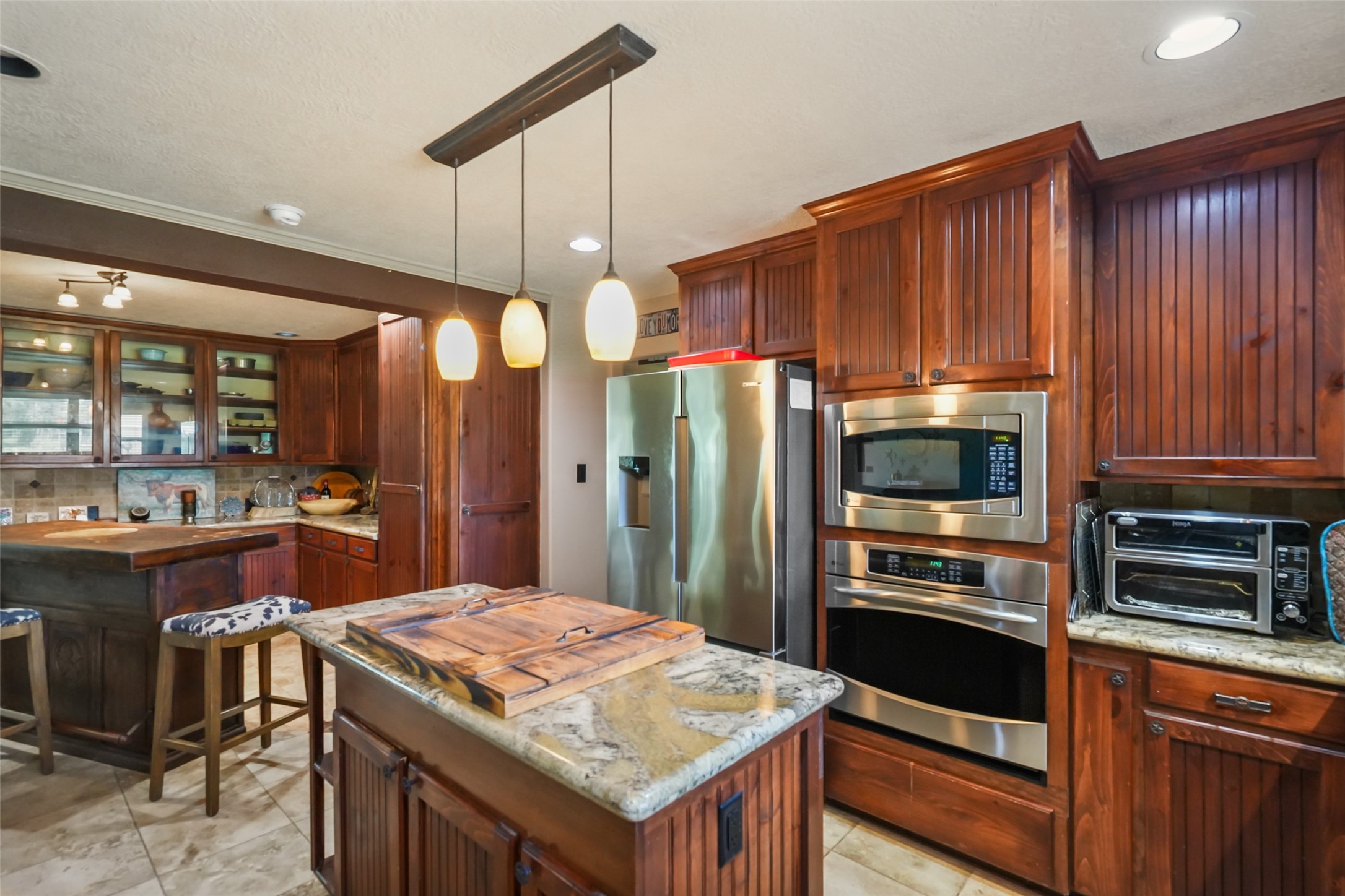 34366 Owens Road Hempstead, TX 77445 - Photo 12 of 46 Gourmet kitchen with custom wood cabinetry, granite countertops, a center island with seating, stainless steel appliances, double ovens, and abundant workspace for cooking and entertaining.
