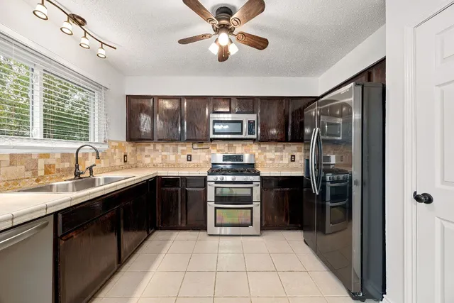 a kitchen with stainless steel appliances granite countertop a refrigerator stove and sink
