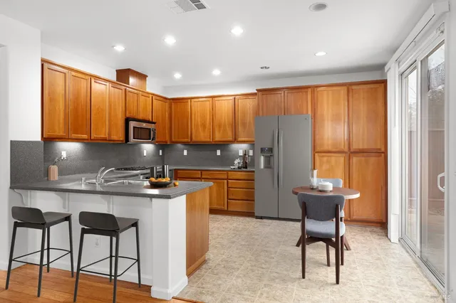 a kitchen with stainless steel appliances granite countertop a refrigerator a sink dishwasher and wooden cabinets with wooden floor