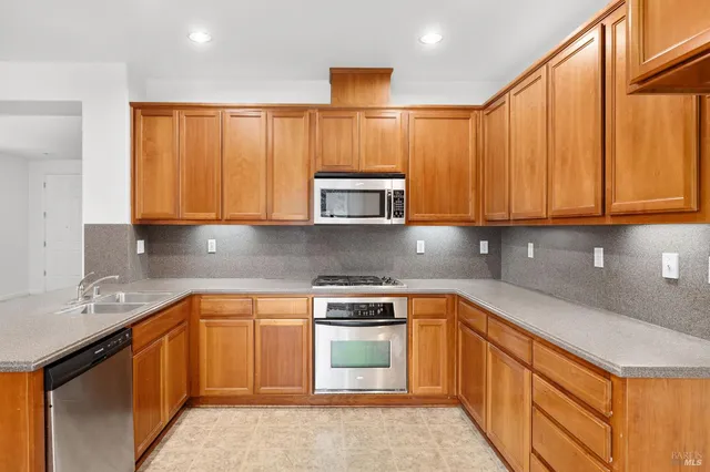 a kitchen with stainless steel appliances granite countertop a sink dishwasher a stove and white countertops with wooden floor