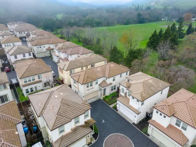 an aerial view of a building with yard and mountain view in back