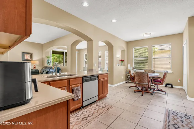 a view of a kitchen with kitchen island granite countertop a large window cabinets a sink and stainless steel appliances