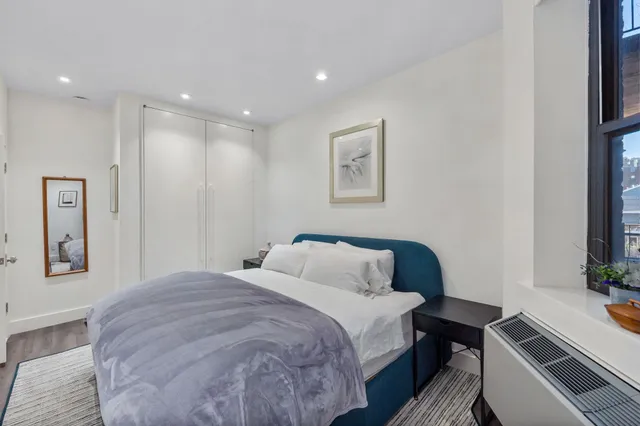 a bedroom with a bed and a potted plant on the dresser