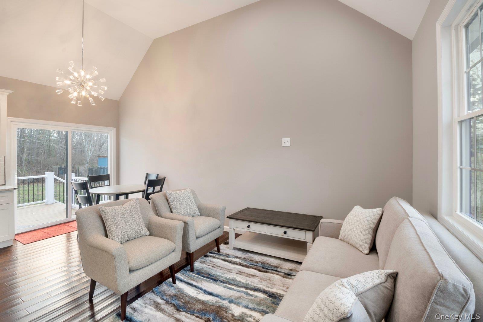 568 Granny Road Medford, NY 11763 - Photo 3 of 22 Living area featuring healthy amount of natural light, a chandelier, wood finished floors, and high vaulted ceiling