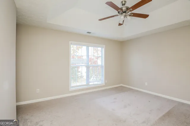 an empty room with windows and fan