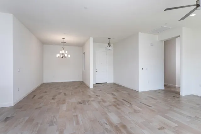 an empty room with kitchen view and wooden floor