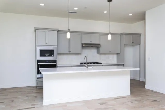 a kitchen with stainless steel appliances granite countertop a sink a stove and a refrigerator