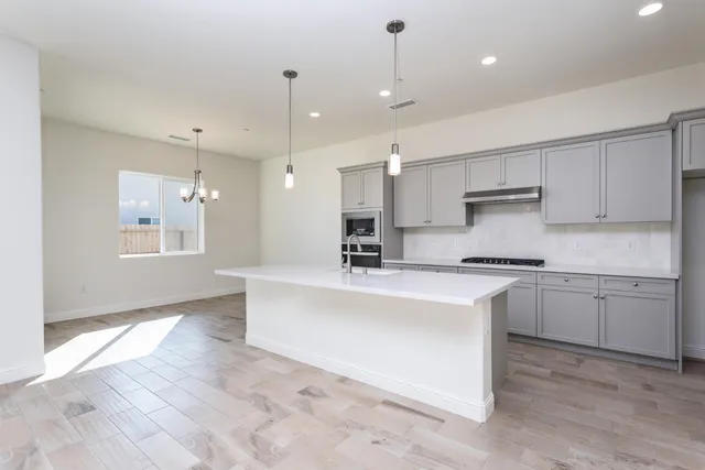 a large kitchen with stainless steel appliances kitchen island granite countertop a sink and white cabinets
