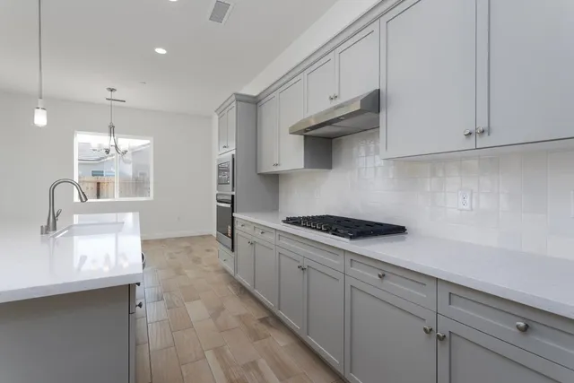 a kitchen with granite countertop a sink a stove and cabinets
