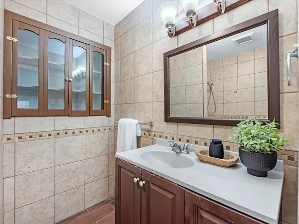 a bathroom with a granite countertop sink a mirror and shower