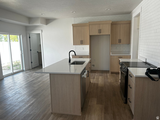 1886 North 300 West Logan, UT 84341 - Photo 6 of 18 Kitchen featuring an island with an undermount sink, light wood-finish cabinetry, subway tile backsplash, and a flat-top electric range