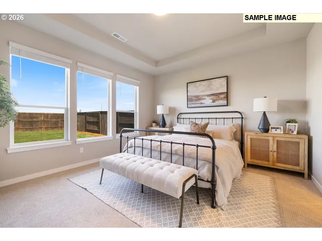 a bedroom with a bed painting on wall and a large window