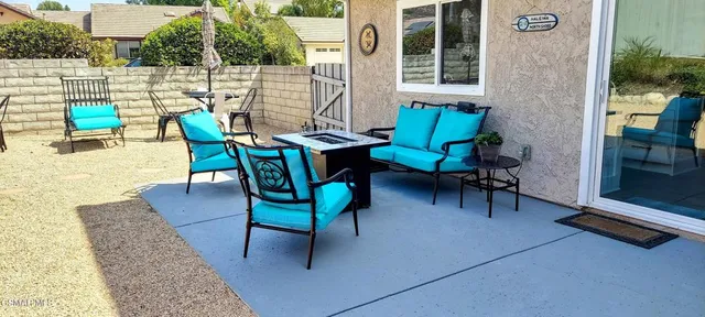 a view of a patio with couches table and chairs under an umbrella with potted plants