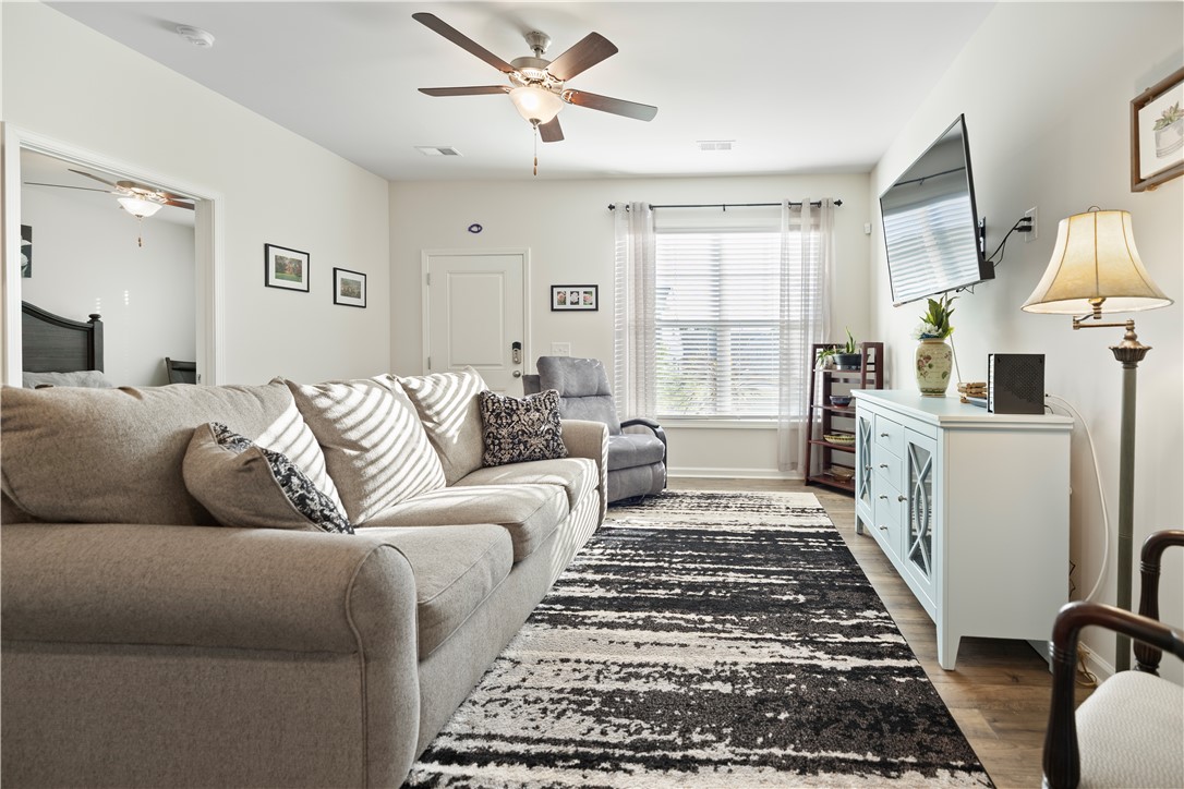 104 Village Main Anderson, SC 29621 - Photo 4 of 30 This bright living space features wood flooring and a modern ceiling fan, creating an inviting atmosphere.