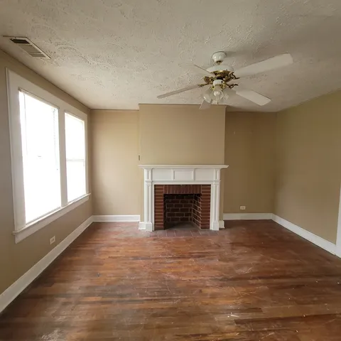 wooden floor fireplace and windows in an empty room