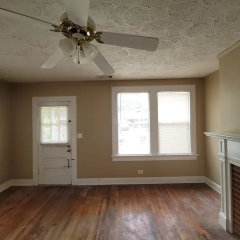an empty room with wooden floor cabinet and windows