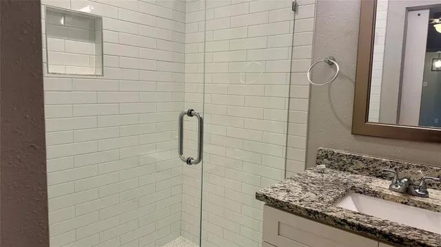 a bathroom with a granite countertop shower a sink and a mirror