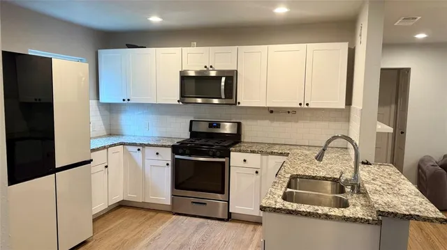 a kitchen with granite countertop a sink stove and refrigerator
