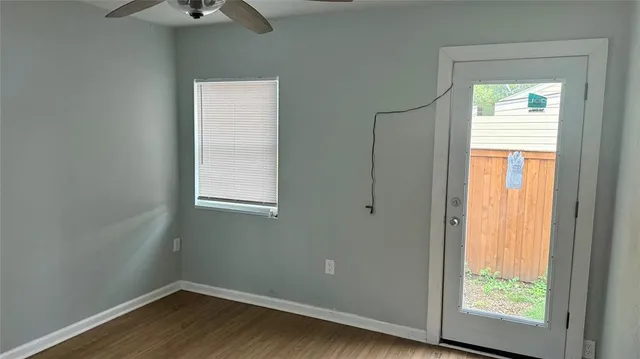 a view of an empty room with wooden floor and a window