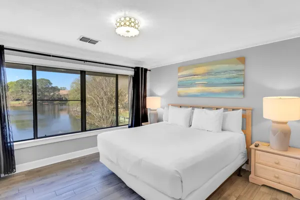 a large white bed in a bedroom next to a window