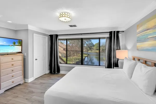 a large bedroom with a bed and a flat tv screen on dresser