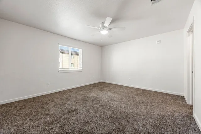 an empty room with a window and a fan