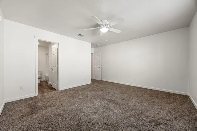 an empty room with a fan & a window