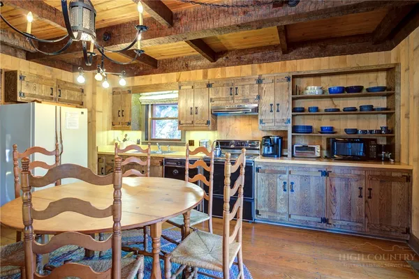 a kitchen with stainless steel appliances granite countertop a table chairs and a wooden floor