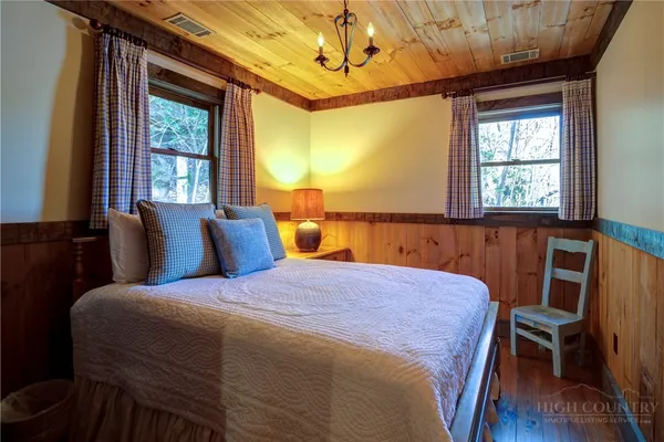 a bedroom with a bed a chandelier and a window