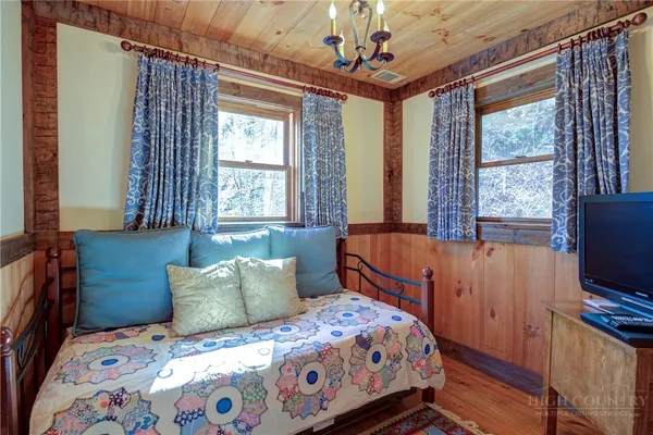 a bedroom with a bed and a flat tv screen on dresser