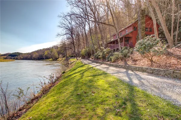 a view of a lake with a yard and large trees