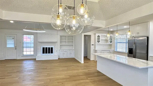 a large kitchen with stainless steel appliances granite countertop a refrigerator a stove and white cabinets with wooden floor