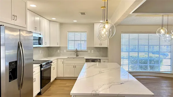 a kitchen with stainless steel appliances granite countertop a sink a stove and refrigerator