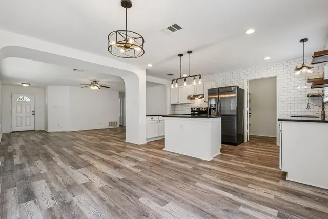 a view of a kitchen with refrigerator and wooden floor