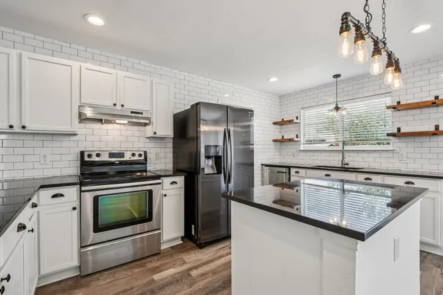 a kitchen with stainless steel appliances granite countertop a sink stove and refrigerator