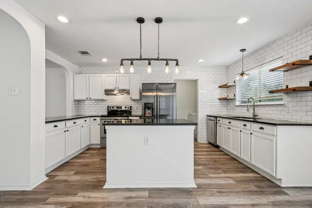 a kitchen with stainless steel appliances granite countertop a sink a stove and a refrigerator