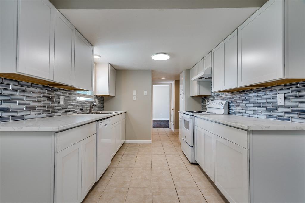 1202 Quill Drive Plano, TX 75075 - Photo 14 of 28 a kitchen with granite countertop a sink and cabinets