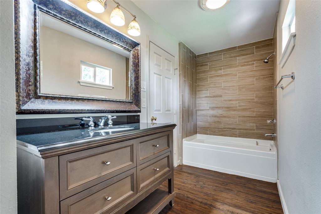 1202 Quill Drive Plano, TX 75075 - Photo 23 of 28 a bathroom with a sink a large mirror and a bathtub