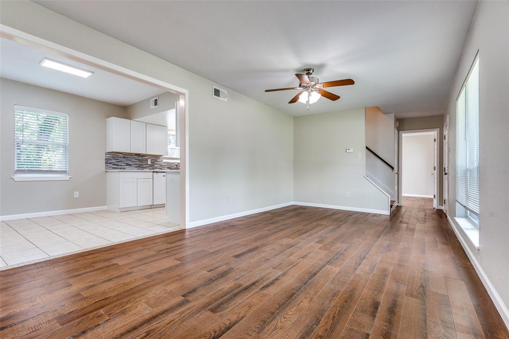 1202 Quill Drive Plano, TX 75075 - Photo 9 of 28 an empty room with wooden floor chandelier fan and windows
