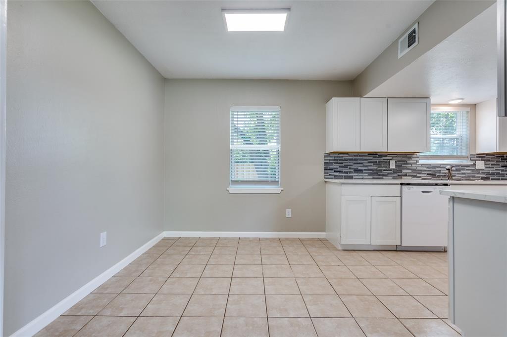 1202 Quill Drive Plano, TX 75075 - Photo 10 of 28 a kitchen with white cabinets a sink a stove and a window
