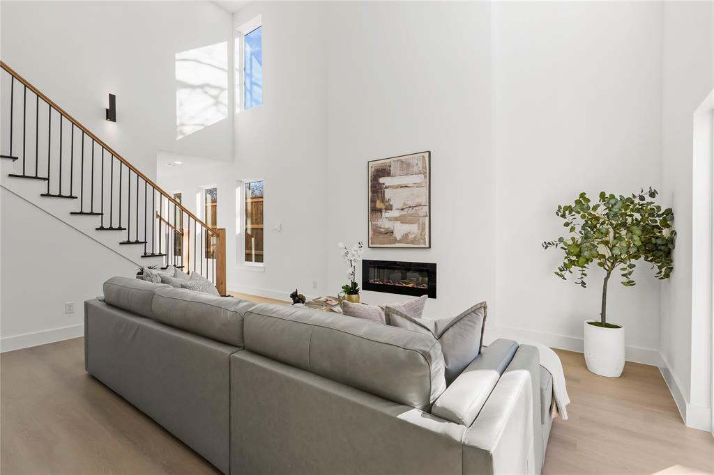 459 Hart Street Dallas, TX 75203 - Photo 5 of 21 Living area with a glass covered fireplace, light wood-style floors, stairway, and a high ceiling